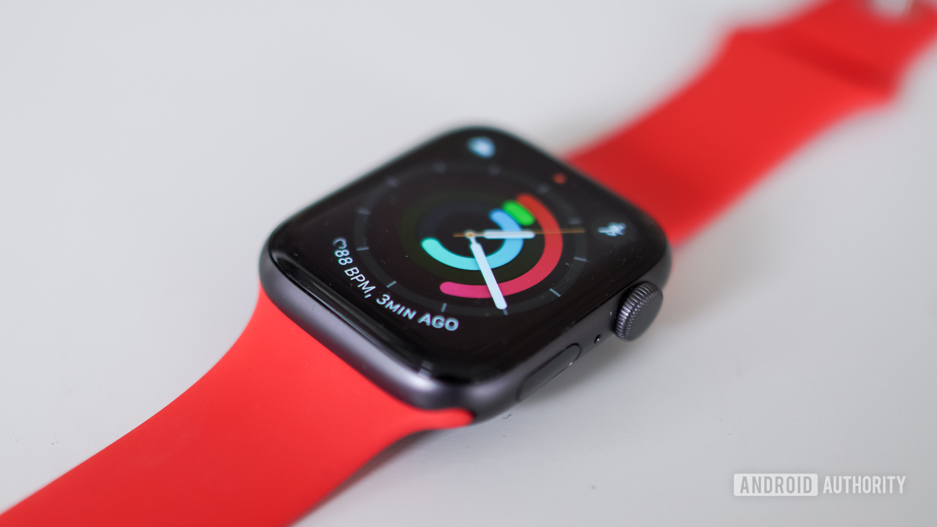 Apple Watch SE在太空灰色的带有红色带的Apple Watch SE位于白色桌子上。