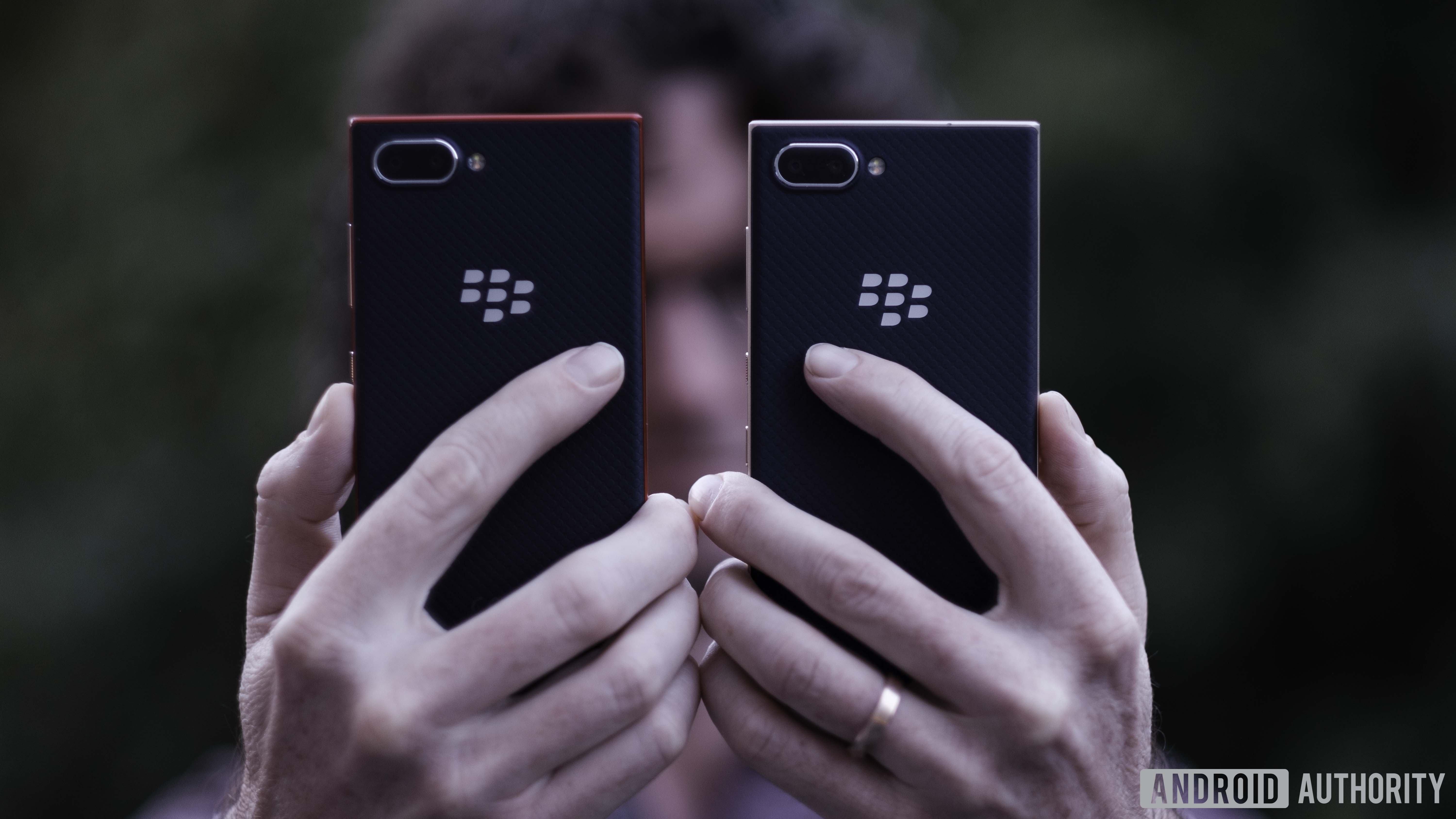 拿着两个BlackBerry key2 Le设备显示背部，相机和黑莓徽标