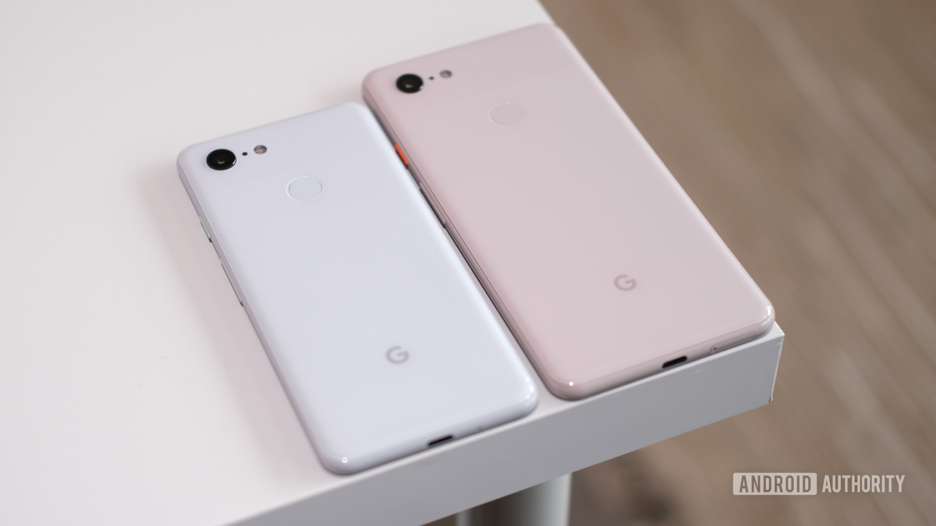 Google Pixel 3中的白色和像素3 XL在桌子上并排粉红色。