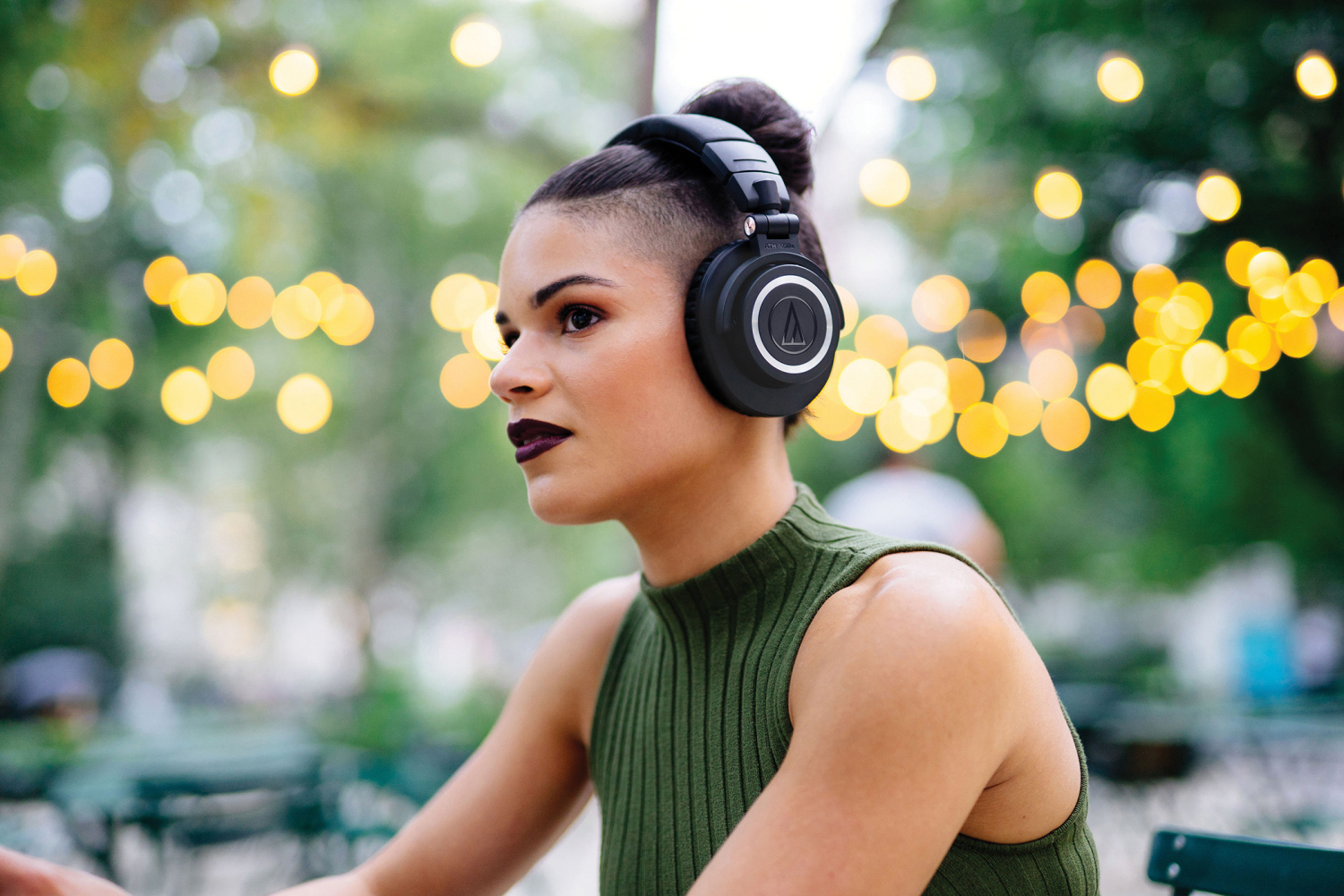 坐在户外戴的女性戴的耳机的音频technica ath-m50xbt生活方式图像。