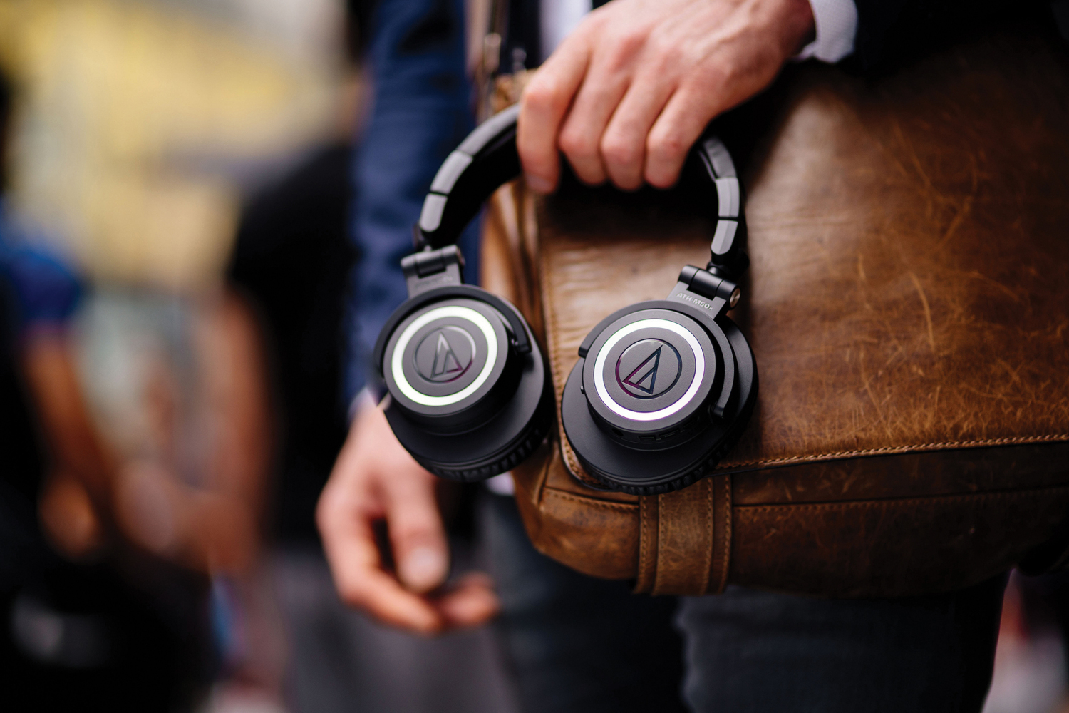 音频technica ath-m50xbt的生活方式图像是男人的手握在皮革允许袋上的耳机。