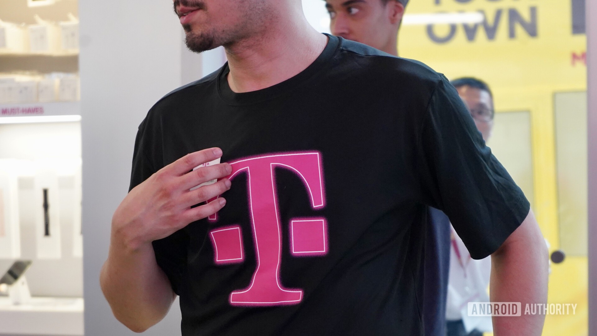 一名T-Mobile员工在穿着带有T-Mobile徽标的黑色T恤时出售T-Mobile 5G服务。