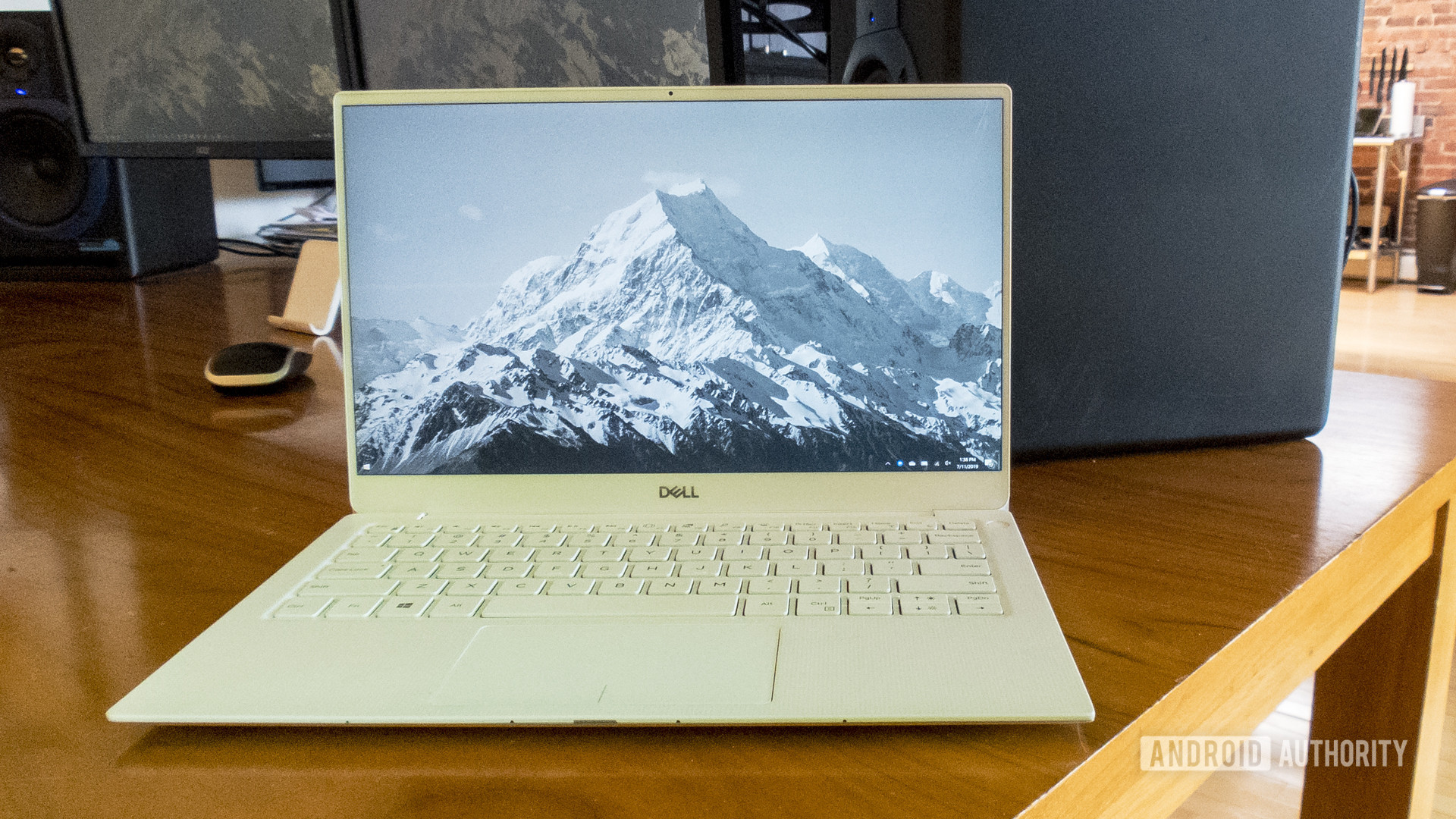 Dell XPS 13 2019版坐在桌子上，带有山景照片作为背景。