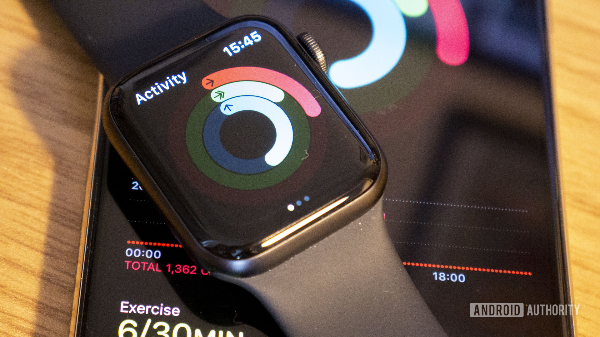 Apple Watch 5放在iPhone上，显示用户活动和卡路里跟踪统计数据。