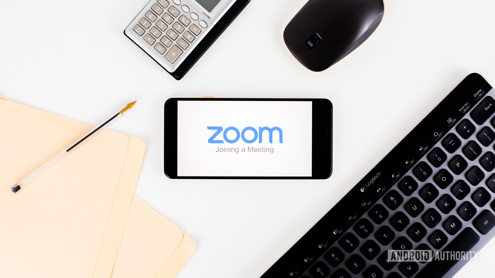在办公设备旁边的智能手机上的缩放会议库存1- Zoom vs Skype