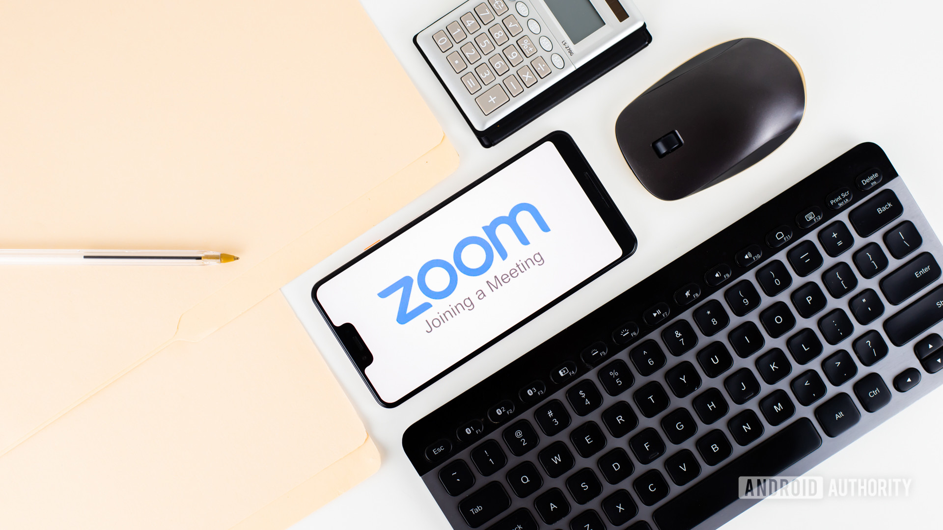 在办公设备旁边的智能手机上的缩放会议库存2- Zoom vs Skype