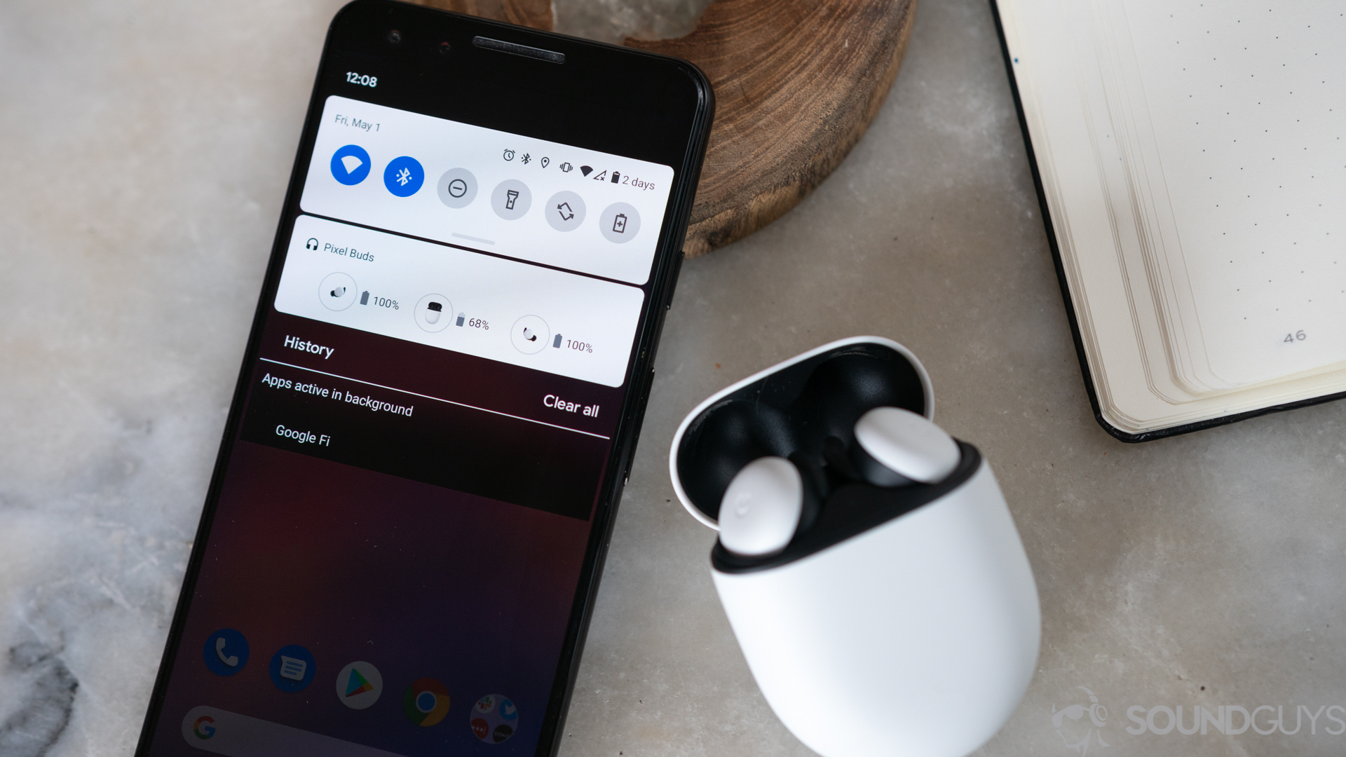 Google Pixel Buds 2020 True无线耳塞盒打开，并在Pixel智能手机旁边显示蓝牙下拉菜单。