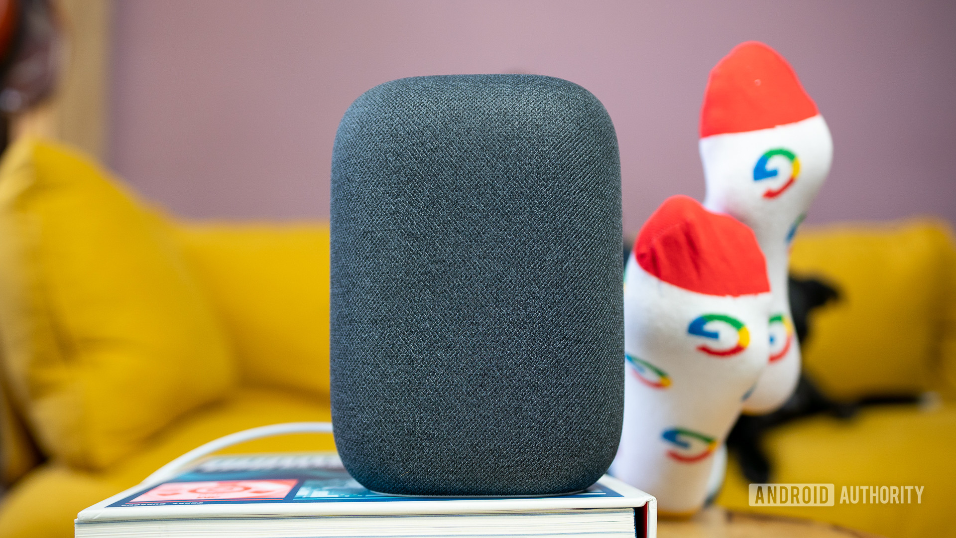 Google Nest Audio在灰色沙发前的书本上灰色。
