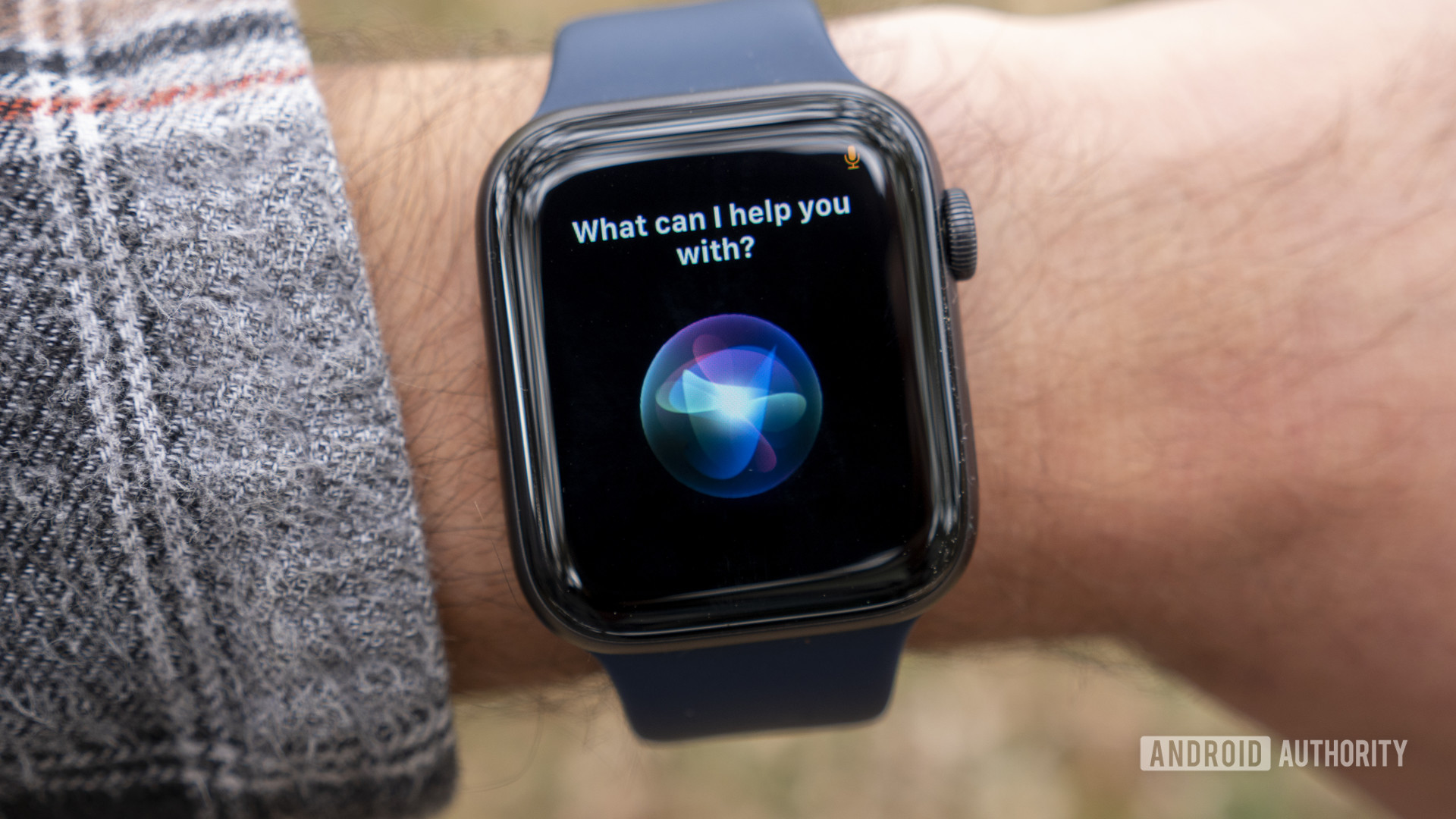 具有太空灰色Apple Watch系列6的用户在手腕上显示Siri Voice Assistant。