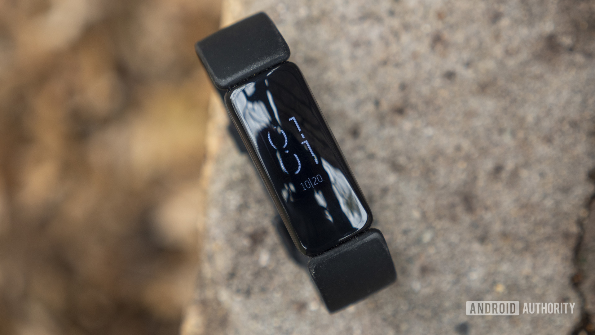 Fitbit Inspire 2放在混凝土壁架上，并显示了手表脸。