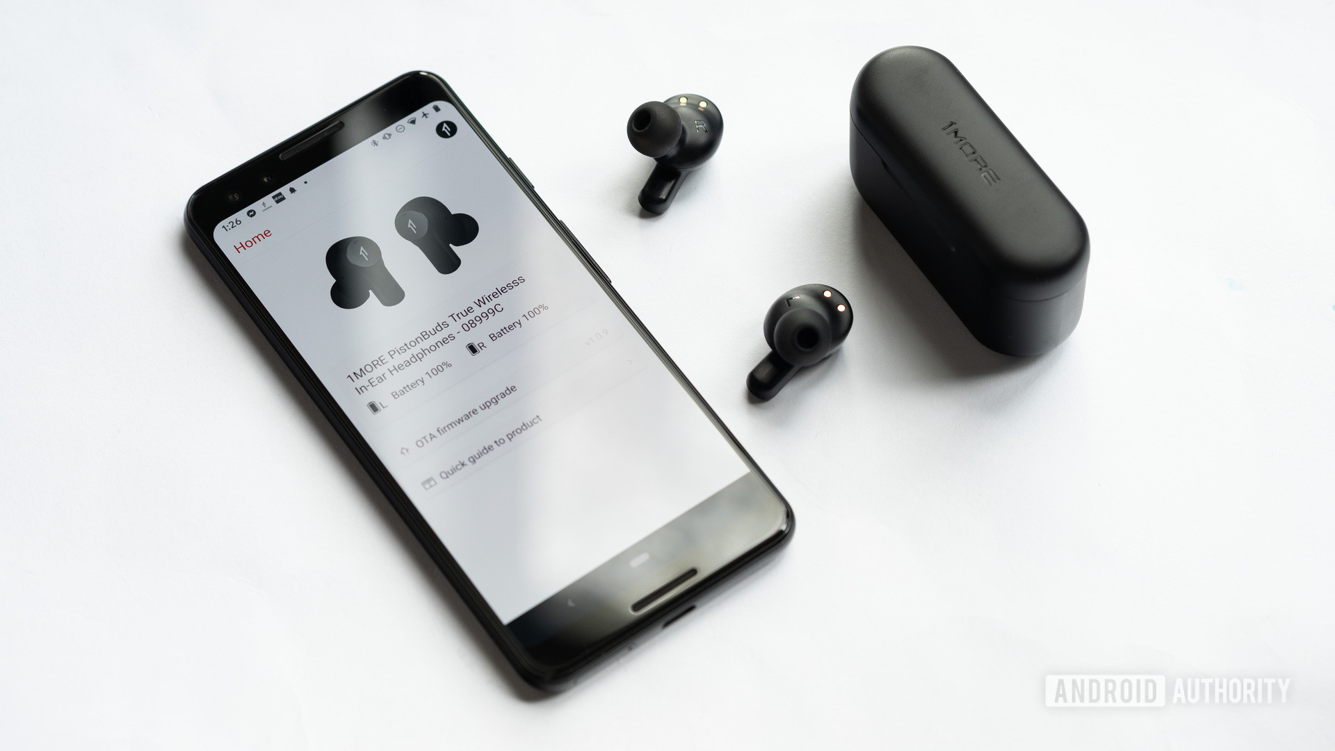 1more Pistonbuds廉价的真实无线耳塞在封闭的充电案例外，在Google Pixel 3智能手机附近，带有1more Music App Open。