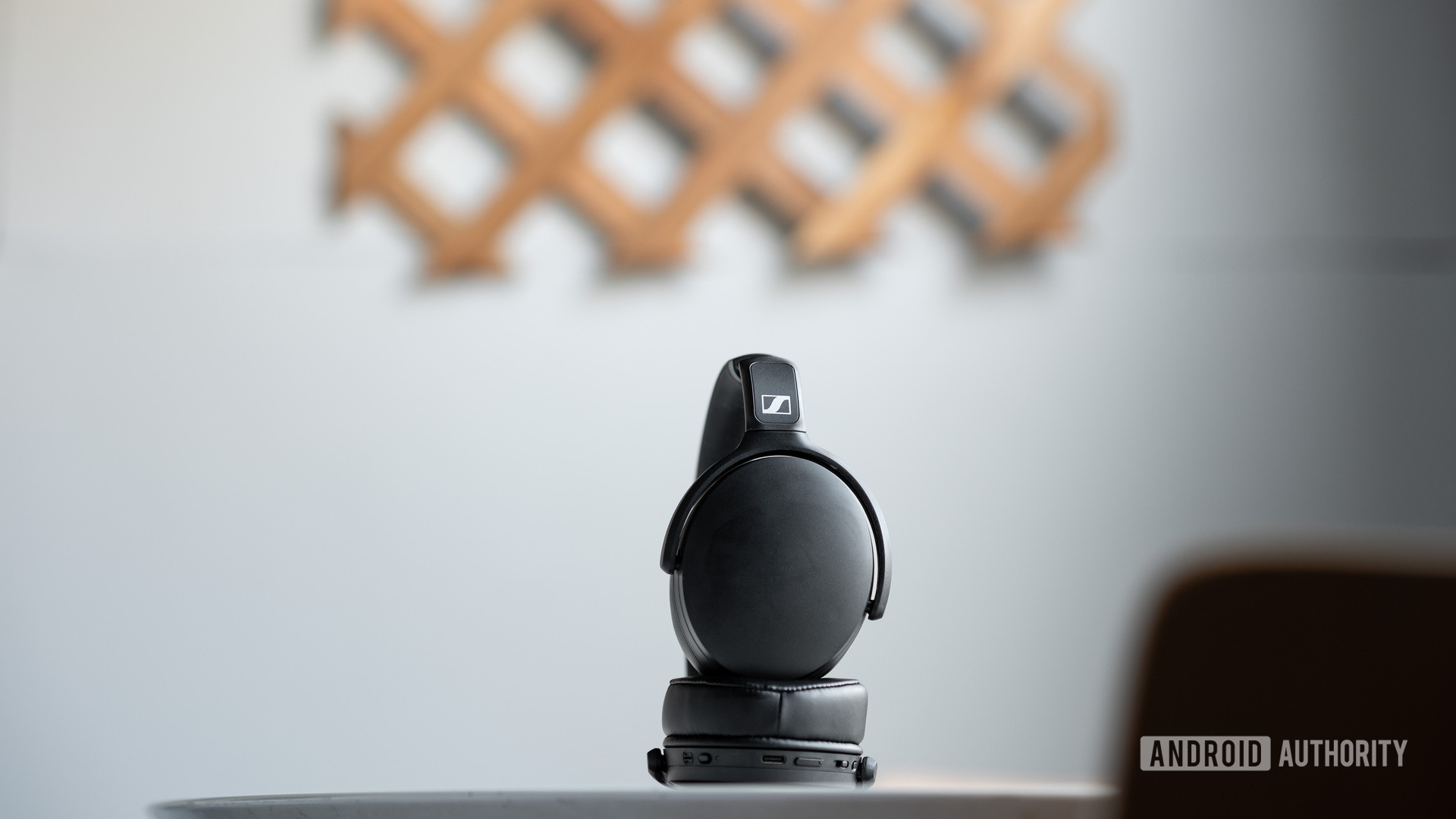Sennheiser HD 350BT蓝牙耳机略微折叠在灰白色墙前的桌子上。
