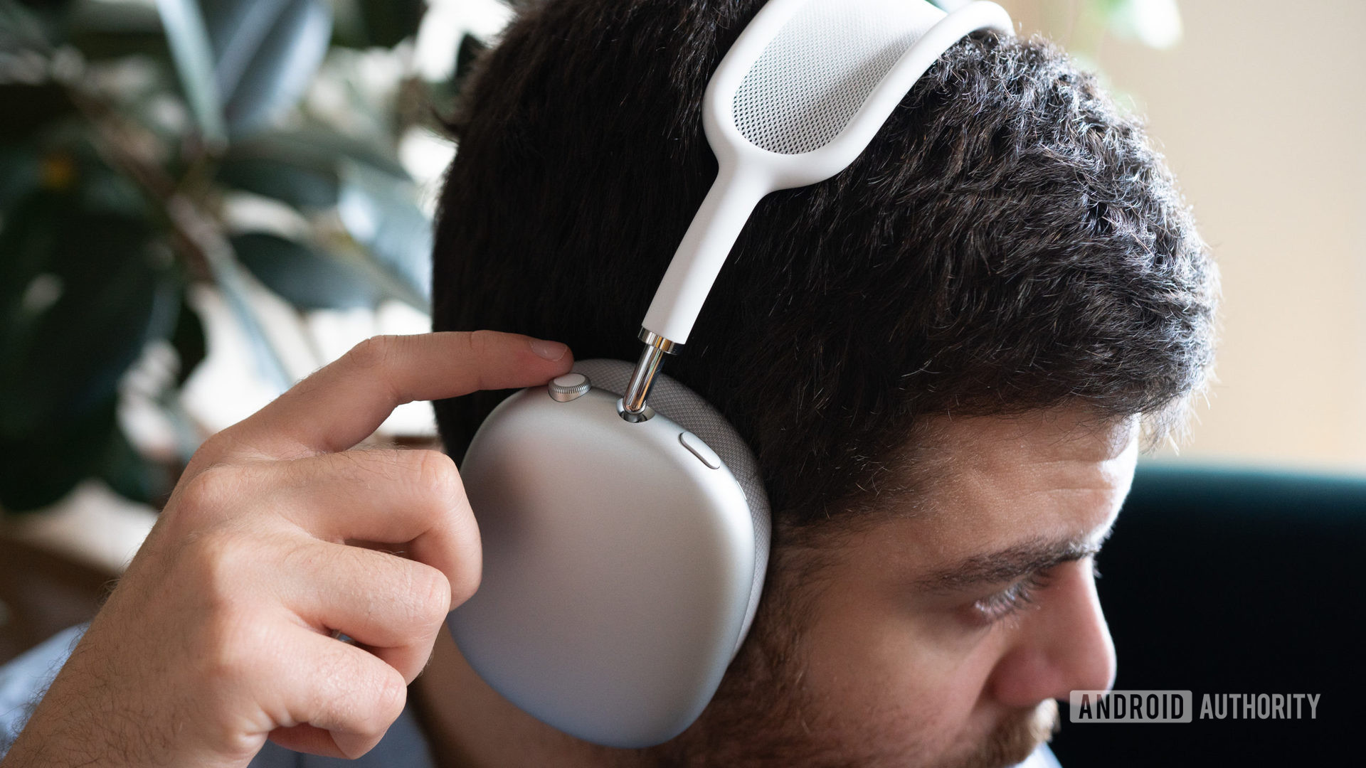 一个人戴上Apple Airpods Max，并使用板载耳机控件。