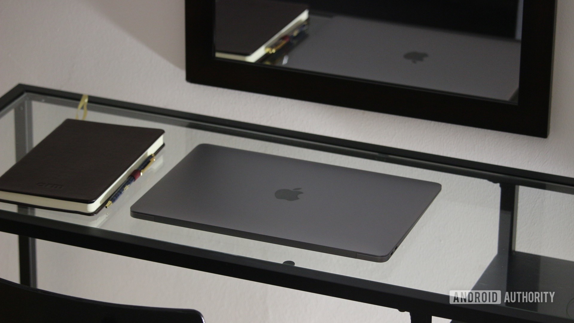 Apple MacBook Air M1在记事本旁边的玻璃桌上