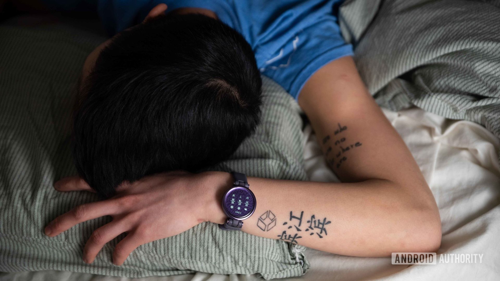 一个女人在左手腕上戴上Garmin Lily Sport Edition智能手表时睡在床上。