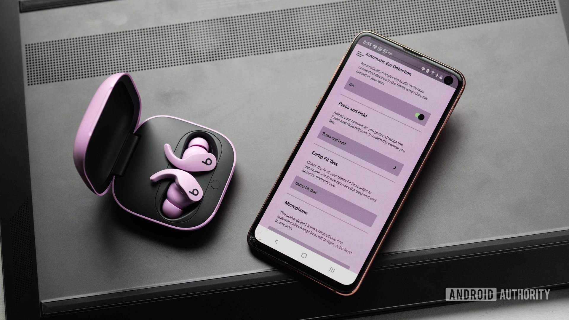 Beats Fit Pro Pro噪声取消真正的无线耳塞，并在Beats应用程序打开的三星Galaxy S10E旁边。该应用具有紫色的色调，大概是为了匹配耳机。