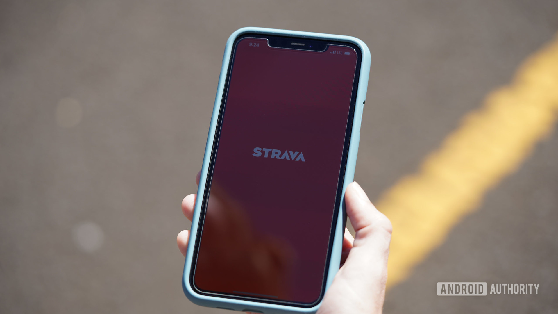 一位女跑步者在其iPhone 11上打开Strava移动应用程序。