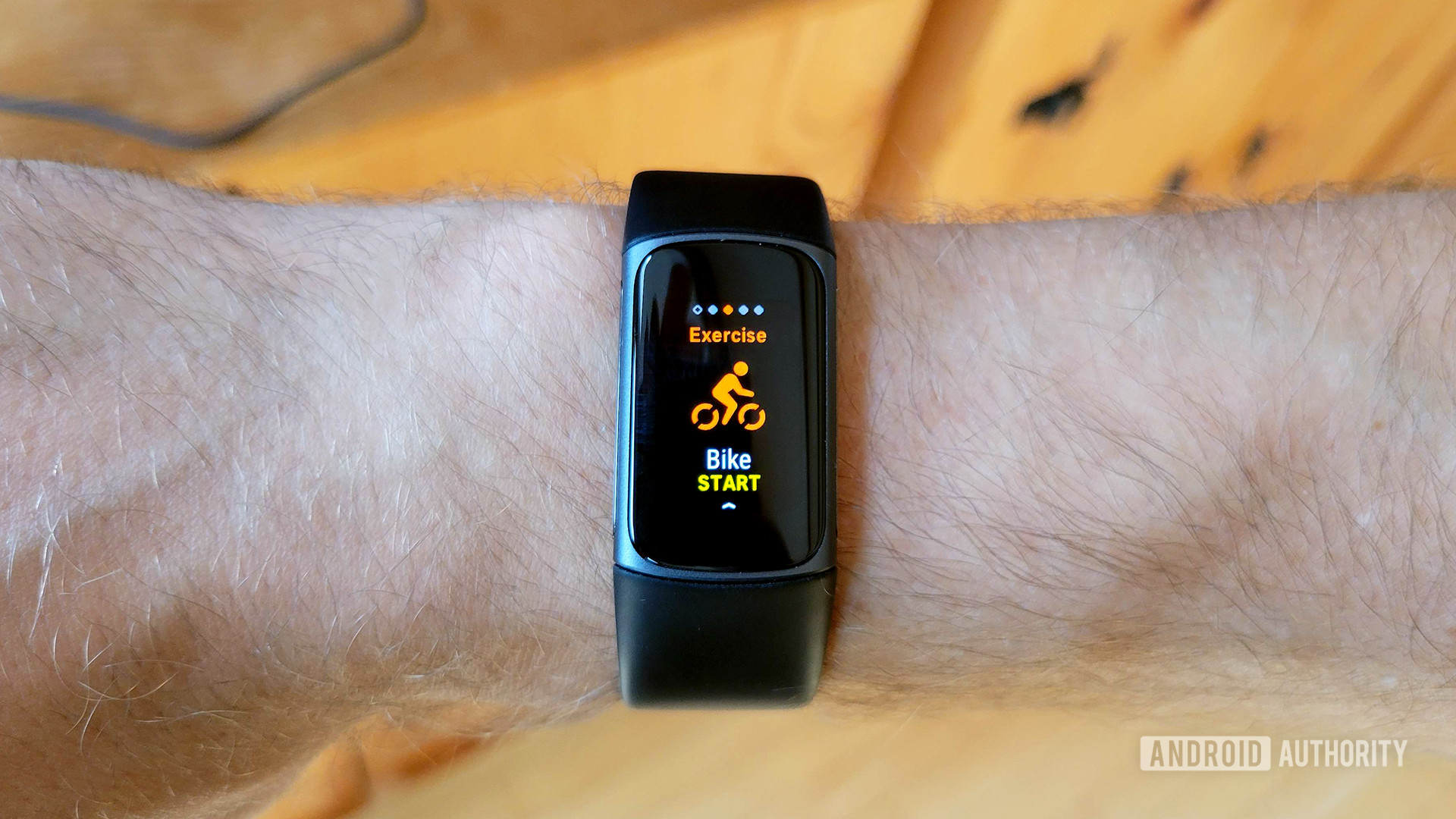 用户手腕上的Fitbit Charge 5显示了开始屏幕自行车练习。