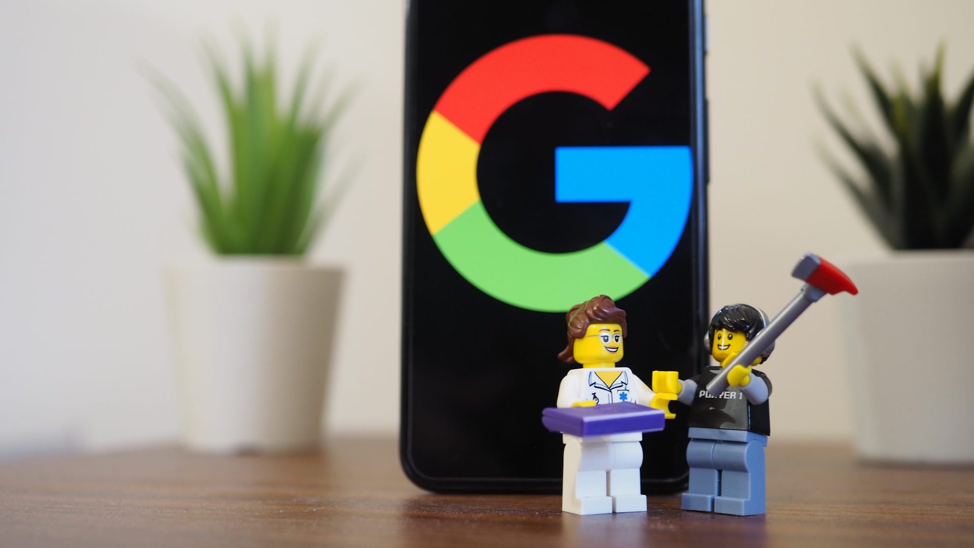 Google Pixel 5在桌子上显示Google徽标，并带有两个乐高雕像