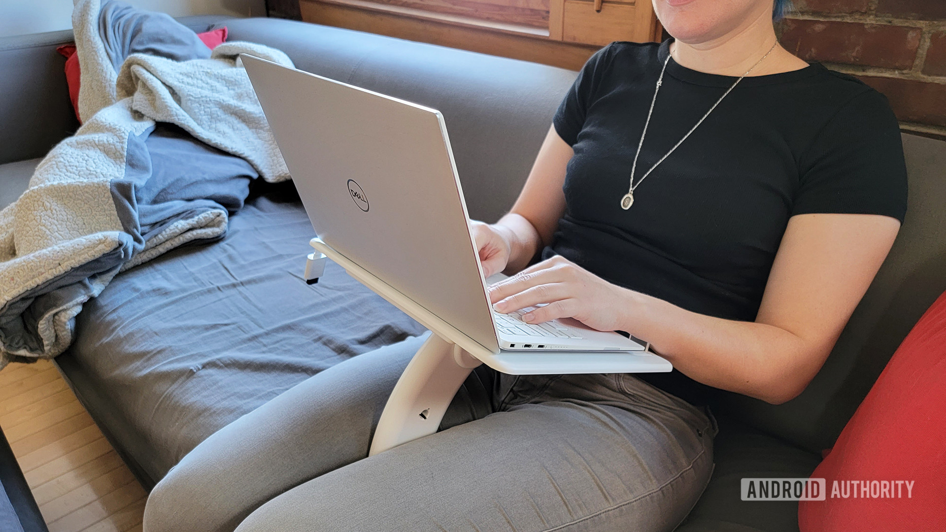 一个女人坐在她的腿上坐在板条圈桌子上，上面有一台戴尔笔记本电脑。